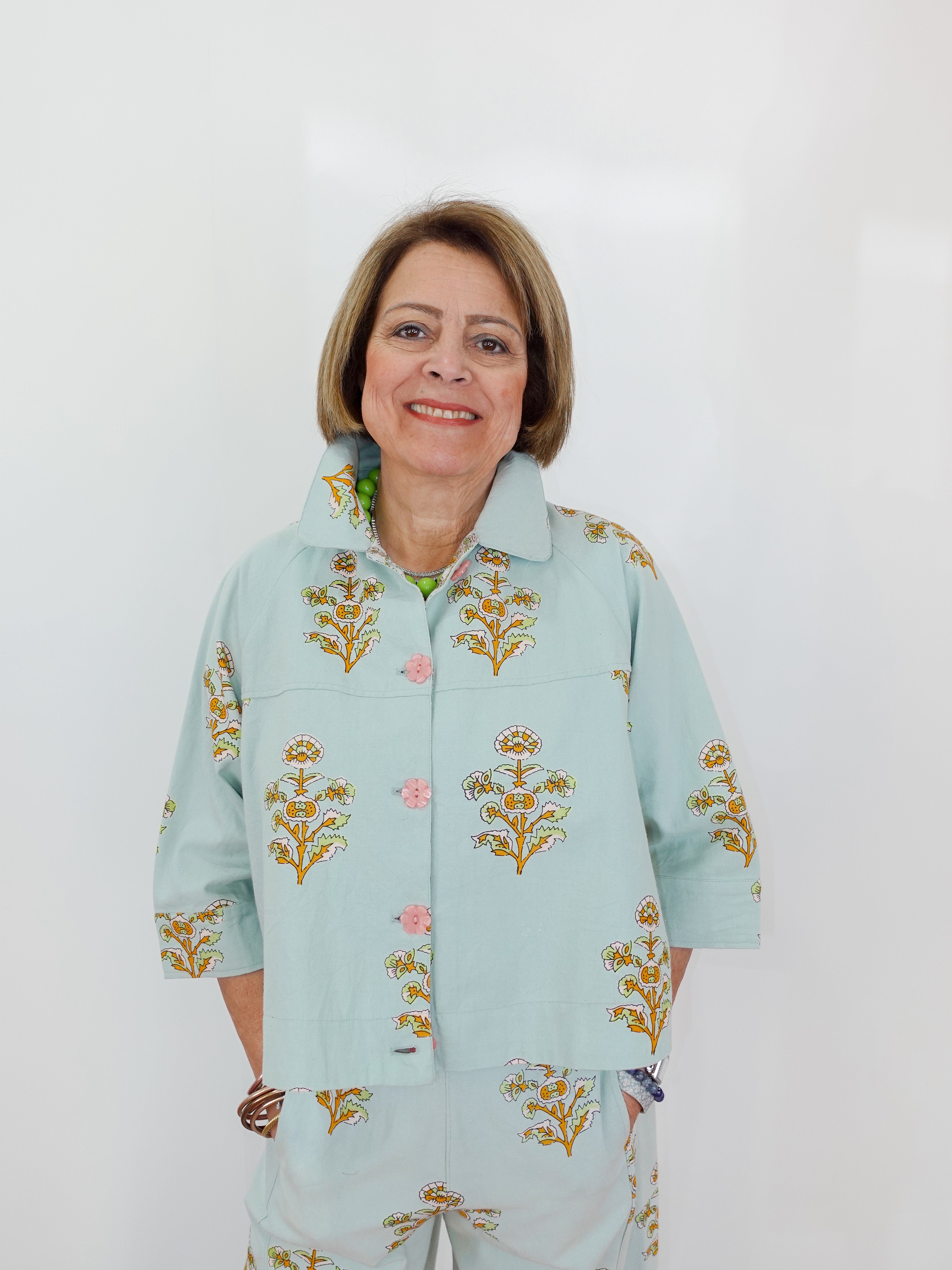 Woman wearing a light blue floral-patterned outfit against a white background