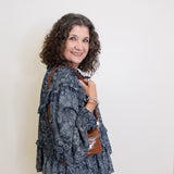 Woman wearing a patterned jacket and holding a brown bag against a white background