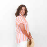 Woman wearing a striped shirt holding a hat against a white background