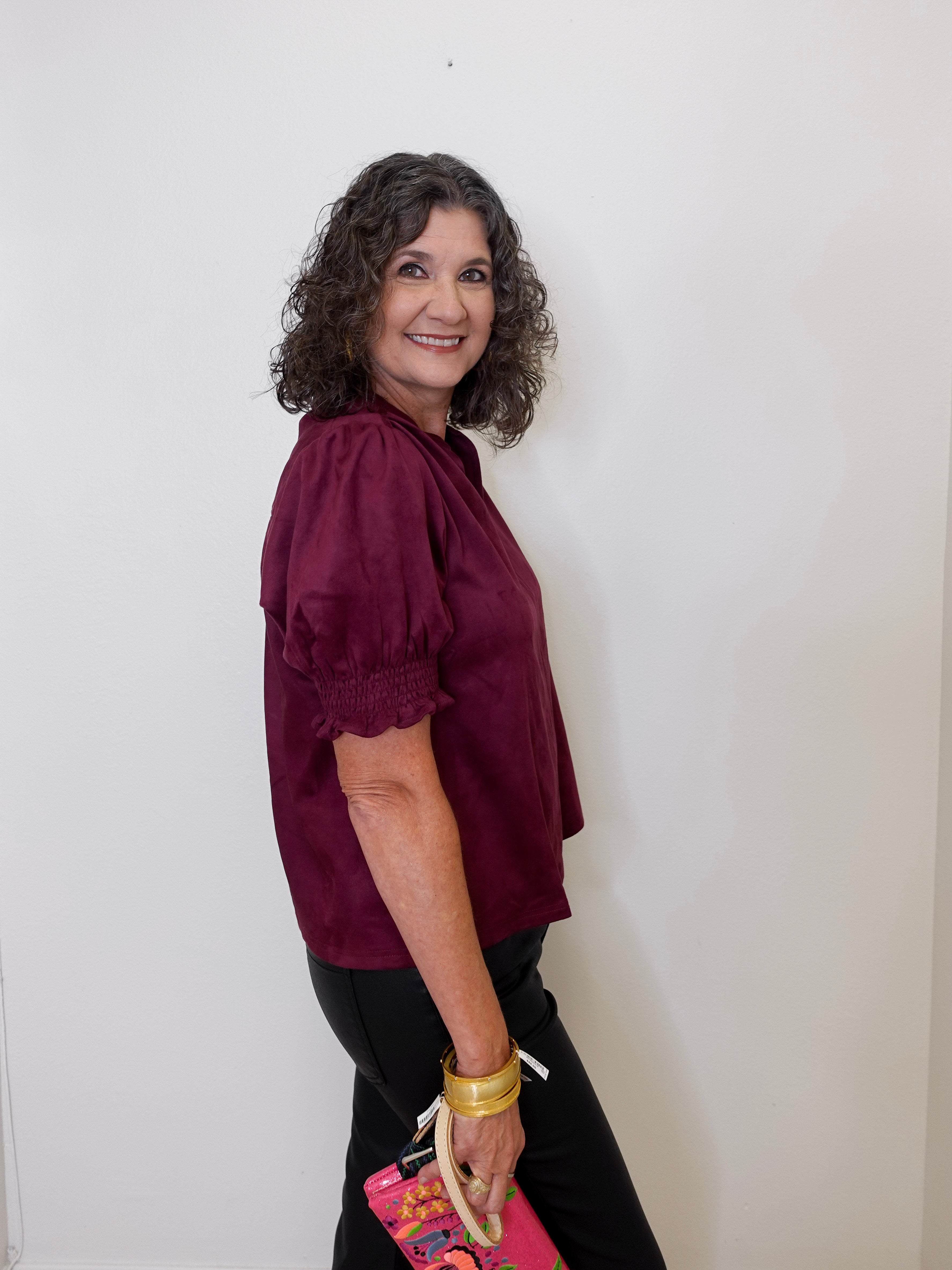 Woman wearing a burgundy blouse against a white wall