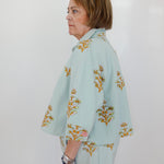 Woman wearing a light blue floral outfit against a white background