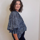 Woman wearing a patterned blue top against a plain background