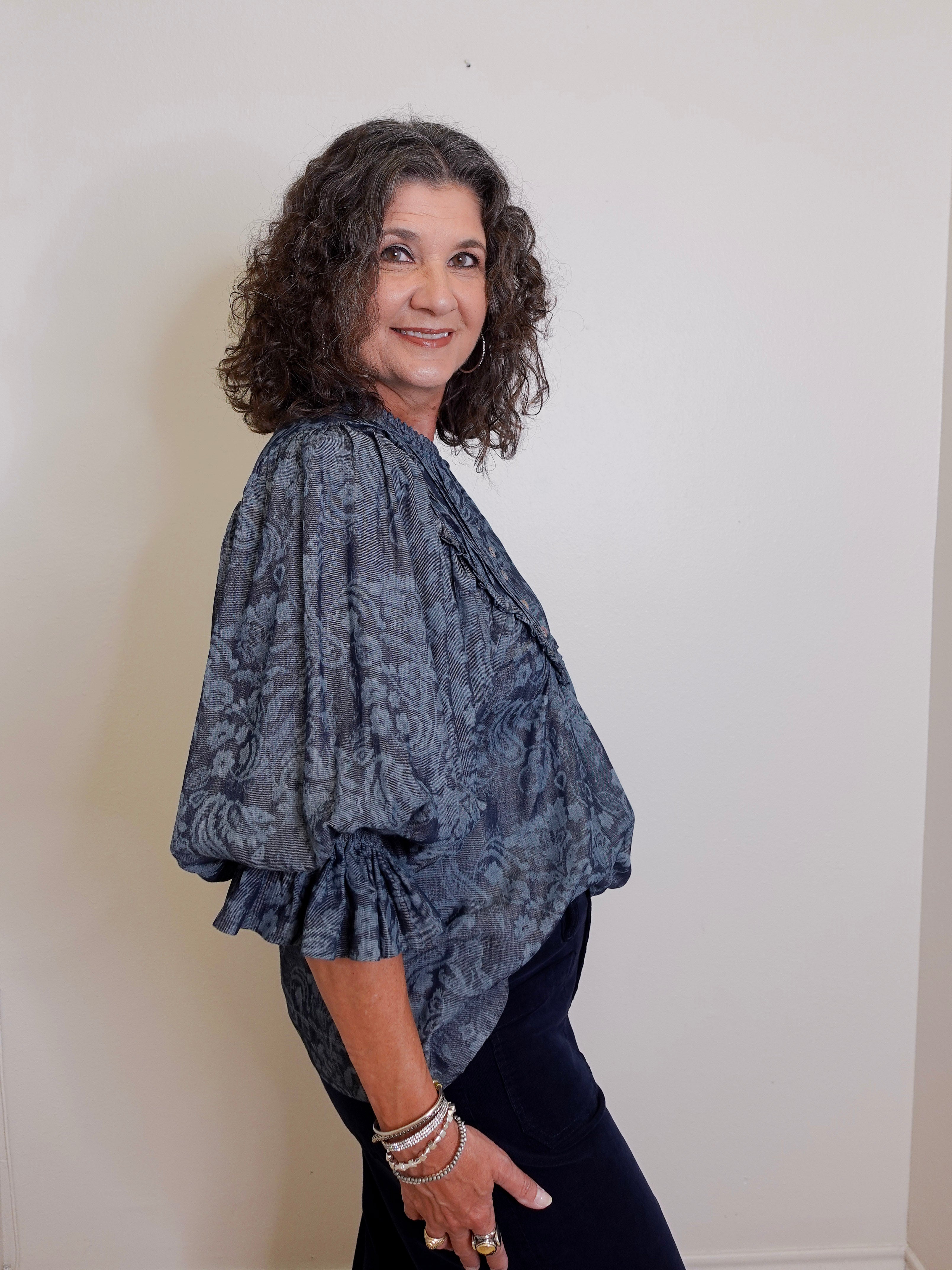 Woman wearing a patterned blue top against a plain background