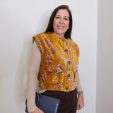 Woman wearing a floral patterned vest against a plain background