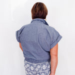 Person wearing a blue shirt and patterned pants against a white background