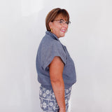 Woman wearing a blue shirt and patterned pants against a white background