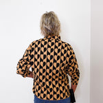 A woman modeling a mock neck heart pattern sweater in front of a white wall. 