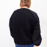 Person wearing a black jacket and blue jeans on a white background