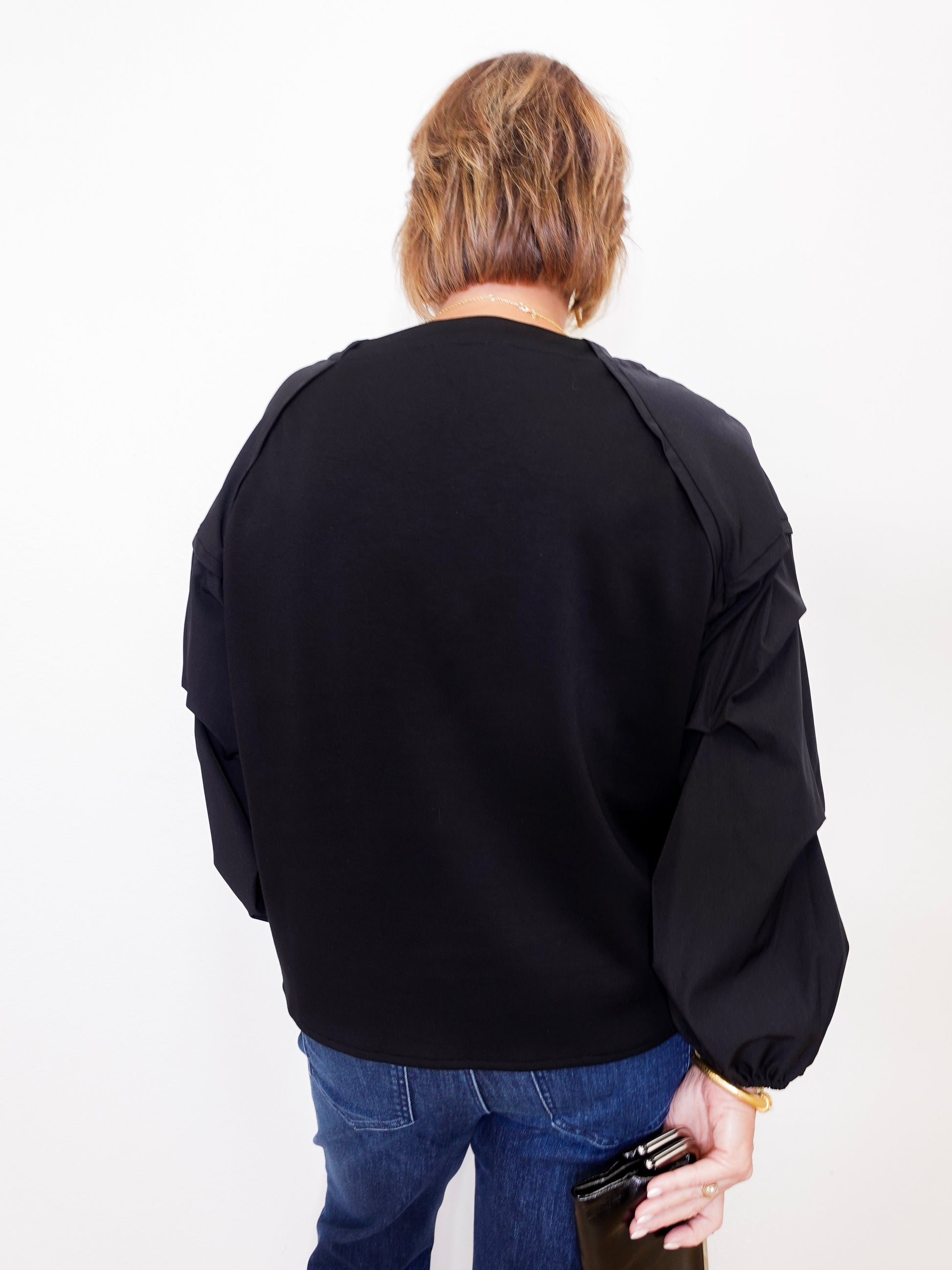 Person wearing a black jacket and blue jeans on a white background