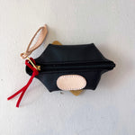 Black pouch with gold zipper and red tassel on a white background
