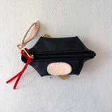 Black pouch with gold zipper and red tassel on a white background