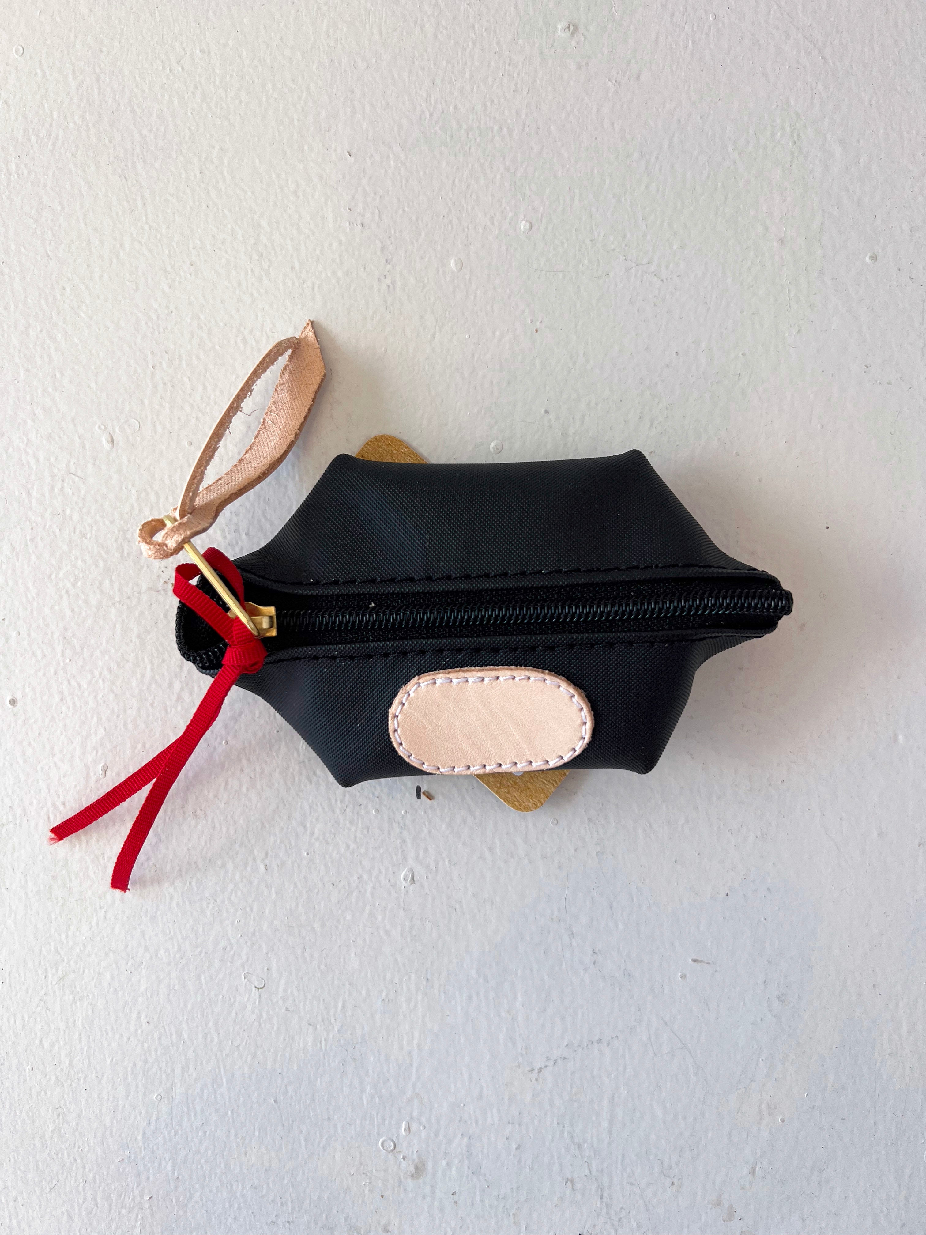 Black pouch with gold zipper and red tassel on a white background