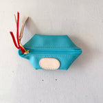 Blue pouch with a gold zipper and red tassels on a white background