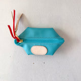 Blue pouch with a gold zipper and red tassels on a white background