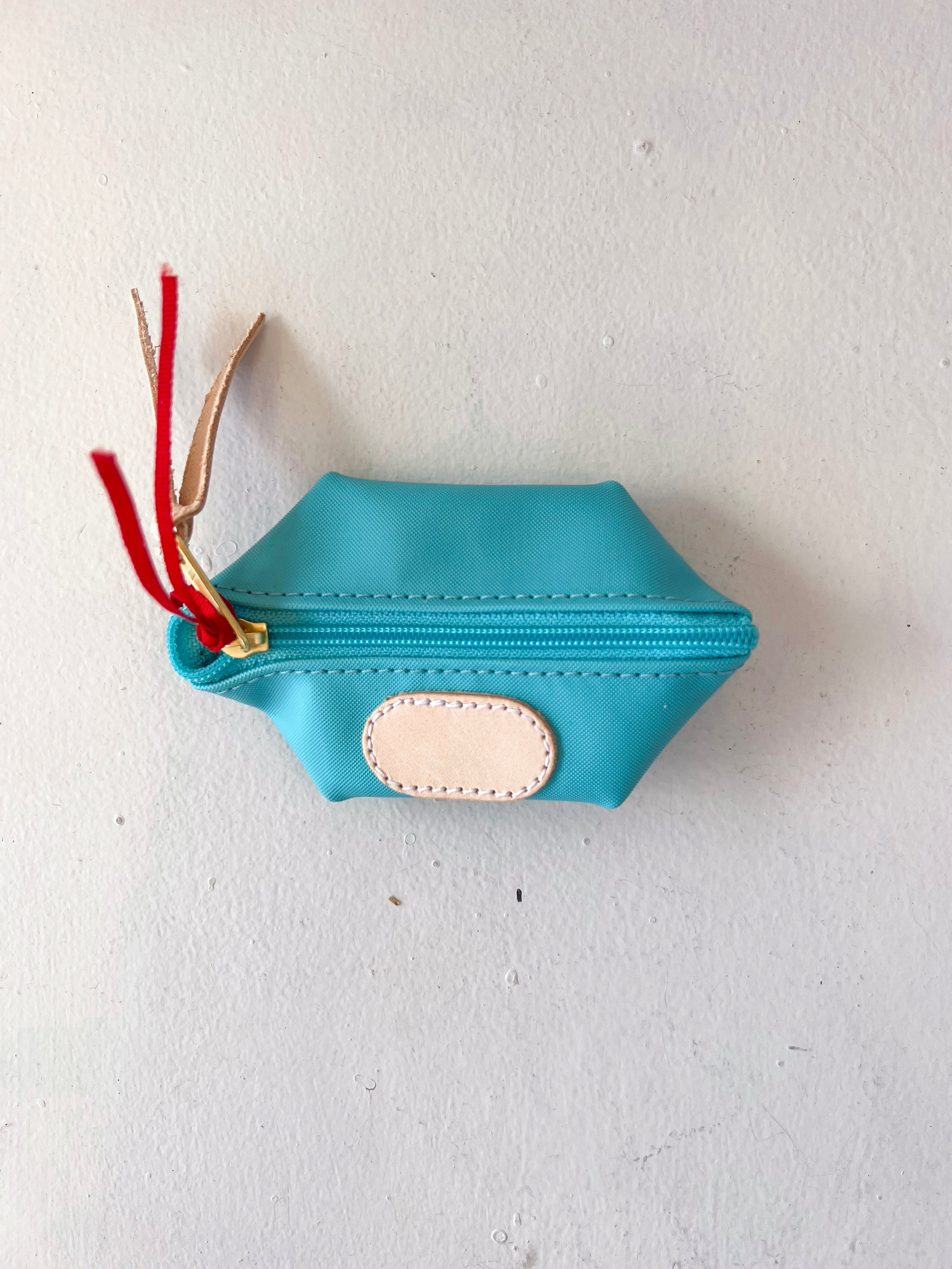 Blue pouch with a gold zipper and red tassels on a white background