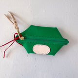 Green hexagonal pouch with a gold zipper and red string on a white background