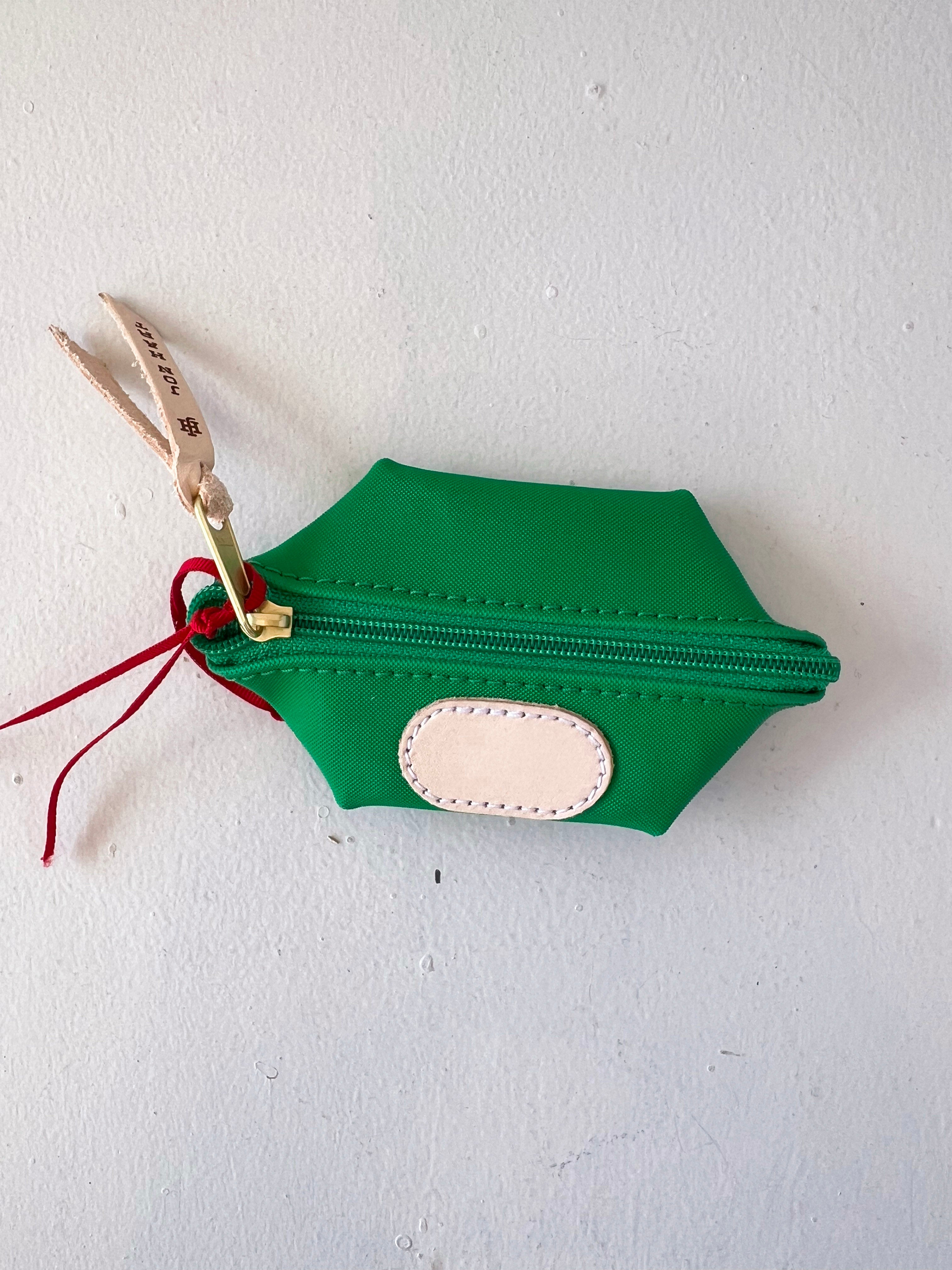 Green hexagonal pouch with a gold zipper and red string on a white background