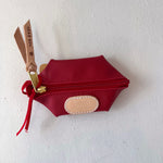 Red pouch with gold scissors attached on a white background