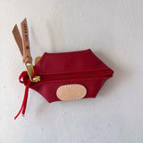 Red pouch with gold scissors attached on a white background