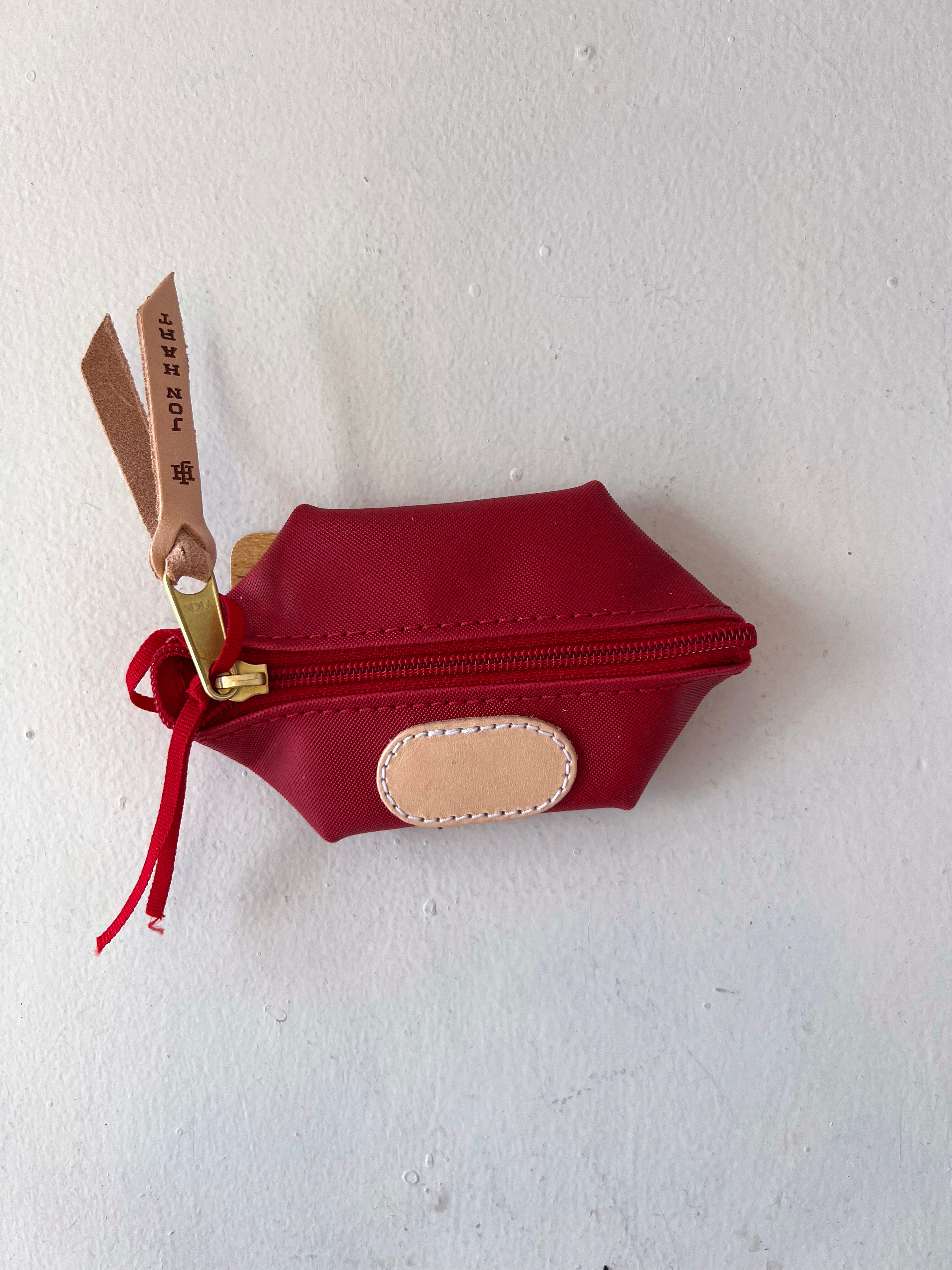 Red pouch with gold scissors attached on a white background
