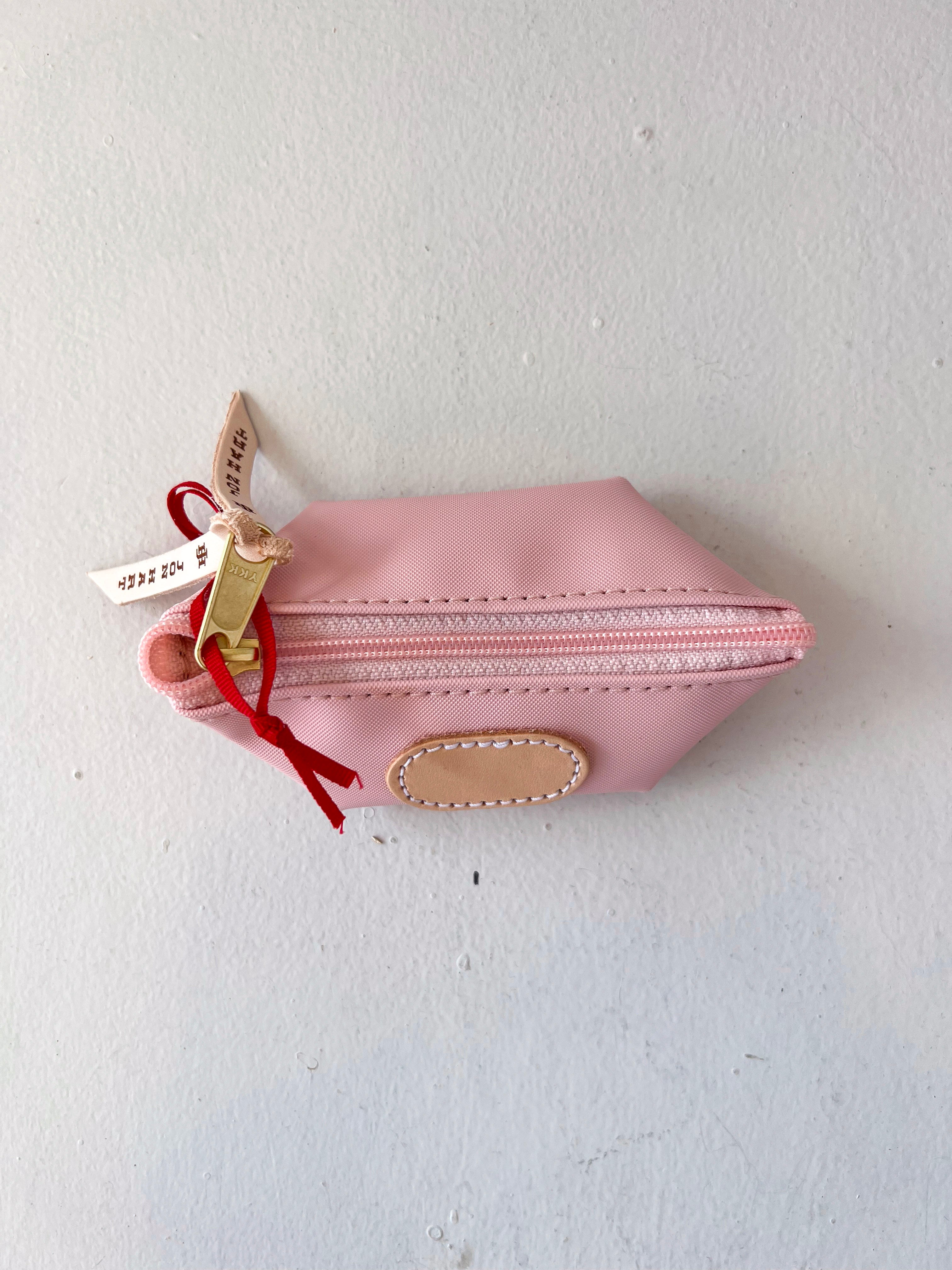 Pink pouch with a gold zipper and red string on a white background