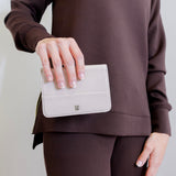woman holding Front view of the HOBO Jill Bi-Fold Wallet in stone gloss aniline leather.