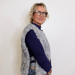 Woman wearing a navy sweater and gray cardigan against a white background