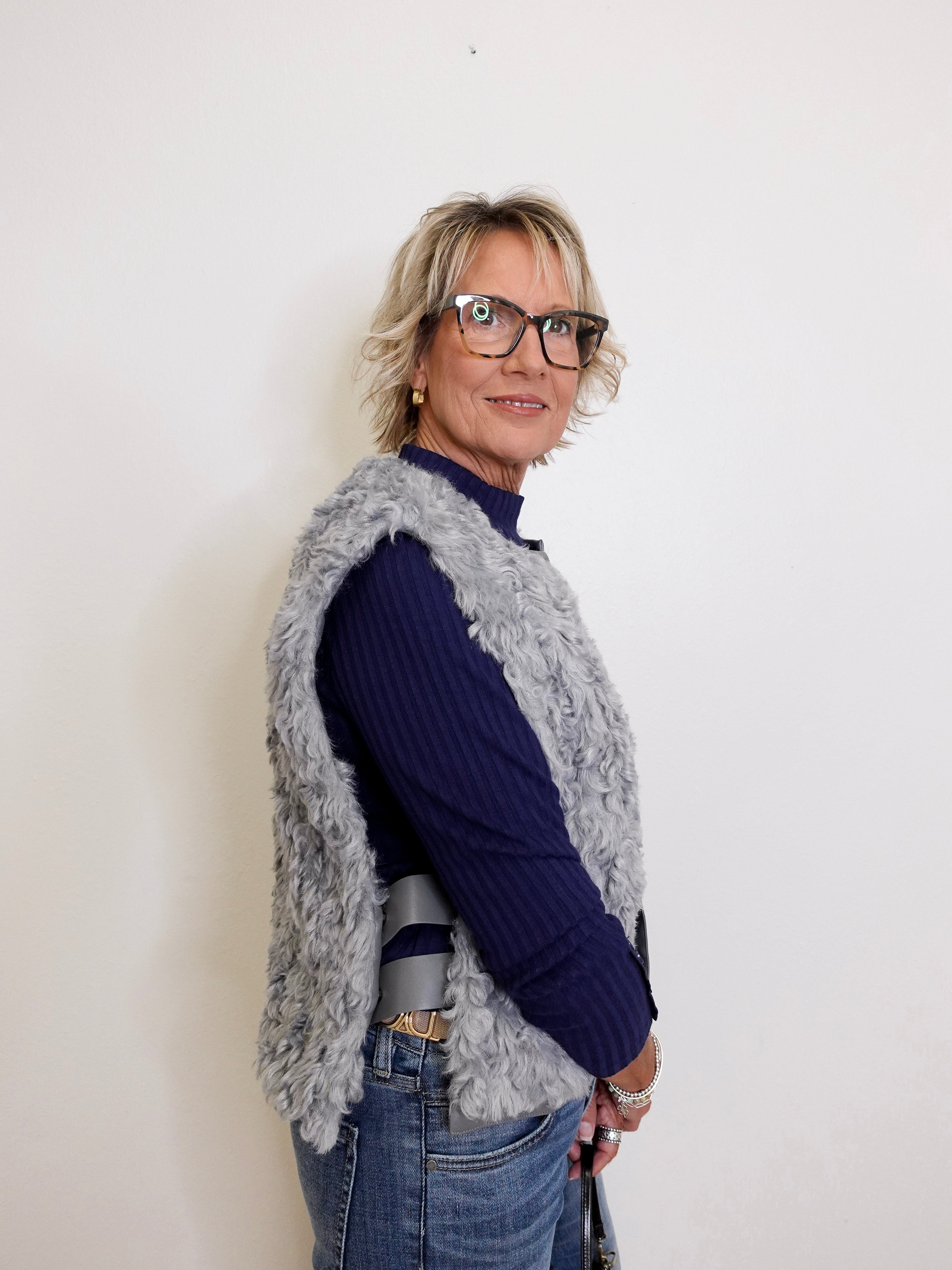 Woman wearing a navy sweater and gray cardigan against a white background