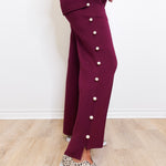 Person wearing a maroon outfit with button details on a light wooden floor.