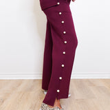 Person wearing a maroon outfit with button details on a light wooden floor.