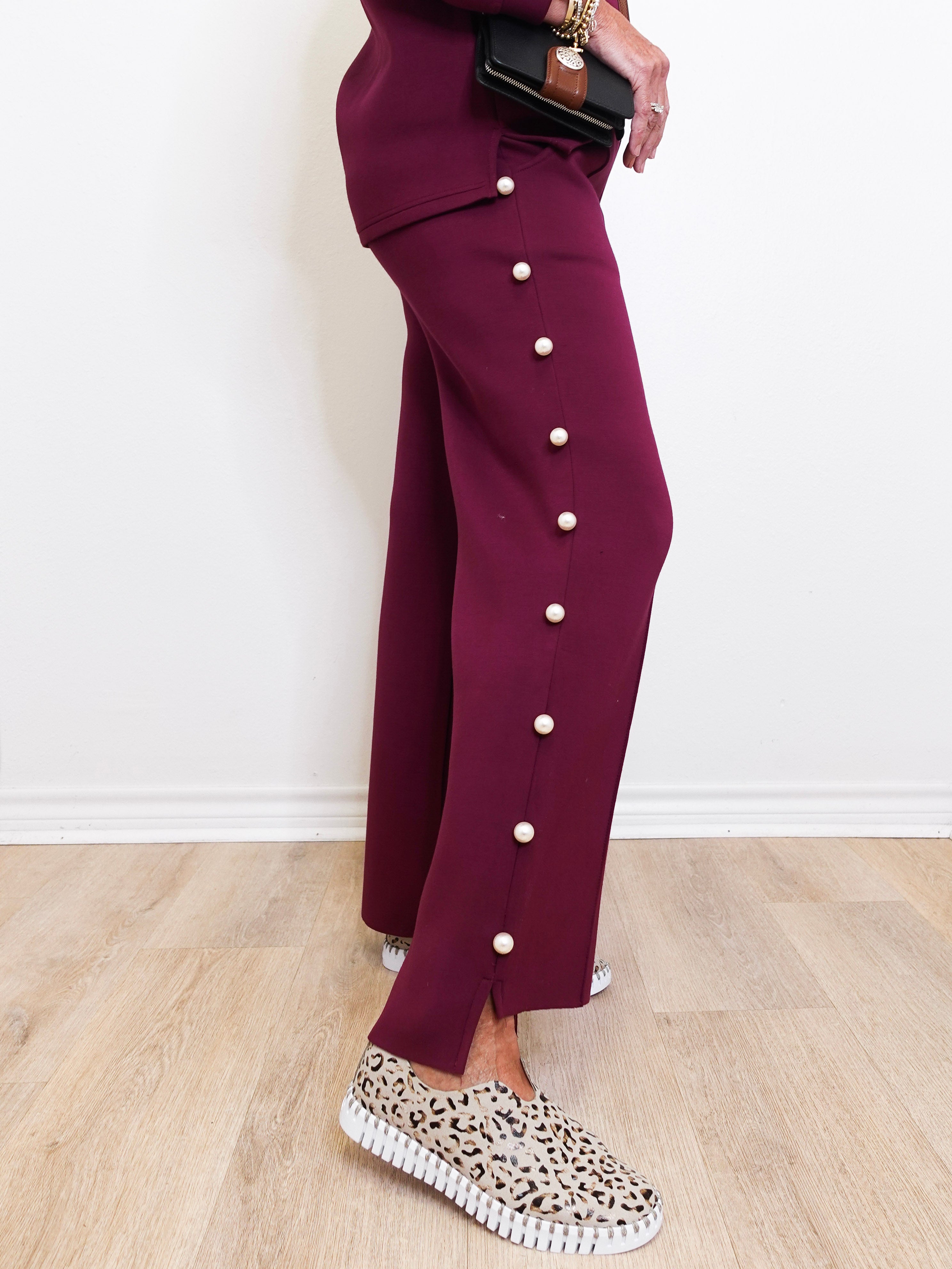 Person wearing a maroon outfit with button details on a light wooden floor.