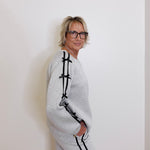 Person wearing a gray tracksuit with black accents against a white wall