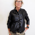Person wearing a black leather jacket and camouflage pants against a white background