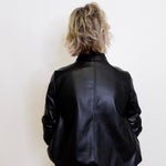 Person wearing a black leather jacket against a white background