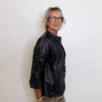 Person wearing a black jacket and camouflage pants against a white background