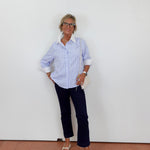 Person wearing a cream outfit with white pants and gray sneakers on a plain background