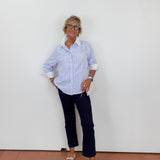 Person wearing a cream outfit with white pants and gray sneakers on a plain background