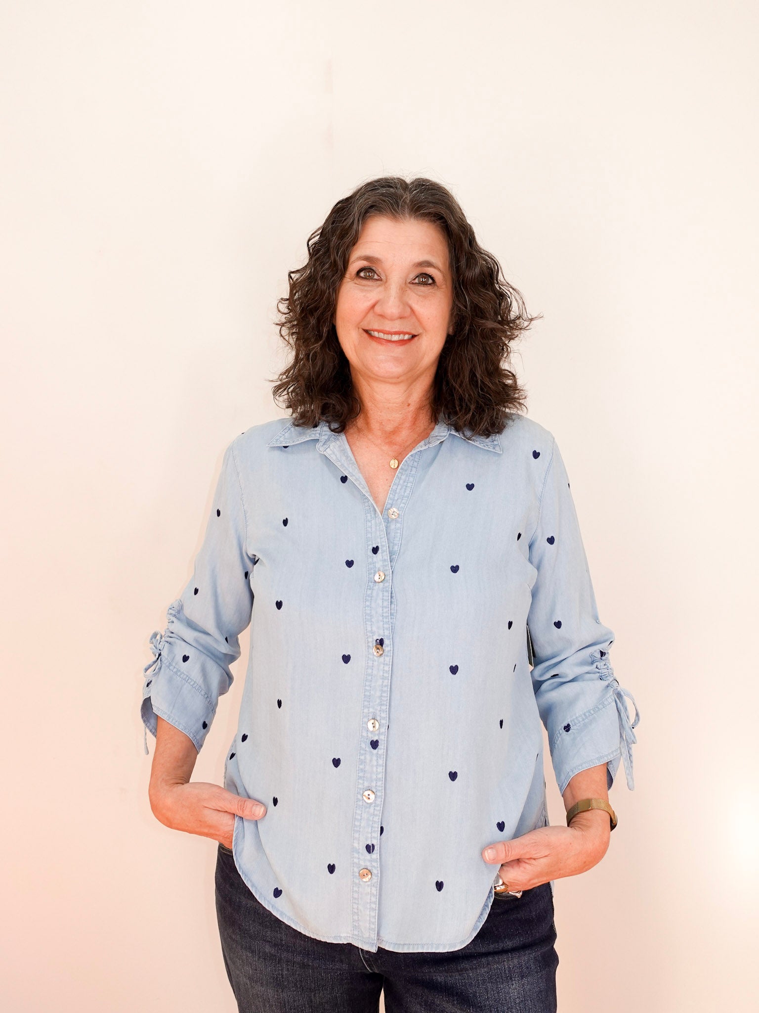 Woman wearing a light blue shirt with black heart patterns on a beige background
