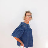 Woman wearing a blue denim top with bead embellishments on a white background