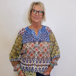 Woman wearing a colorful patterned blouse against a white background