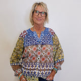 Woman wearing a colorful patterned blouse against a white background