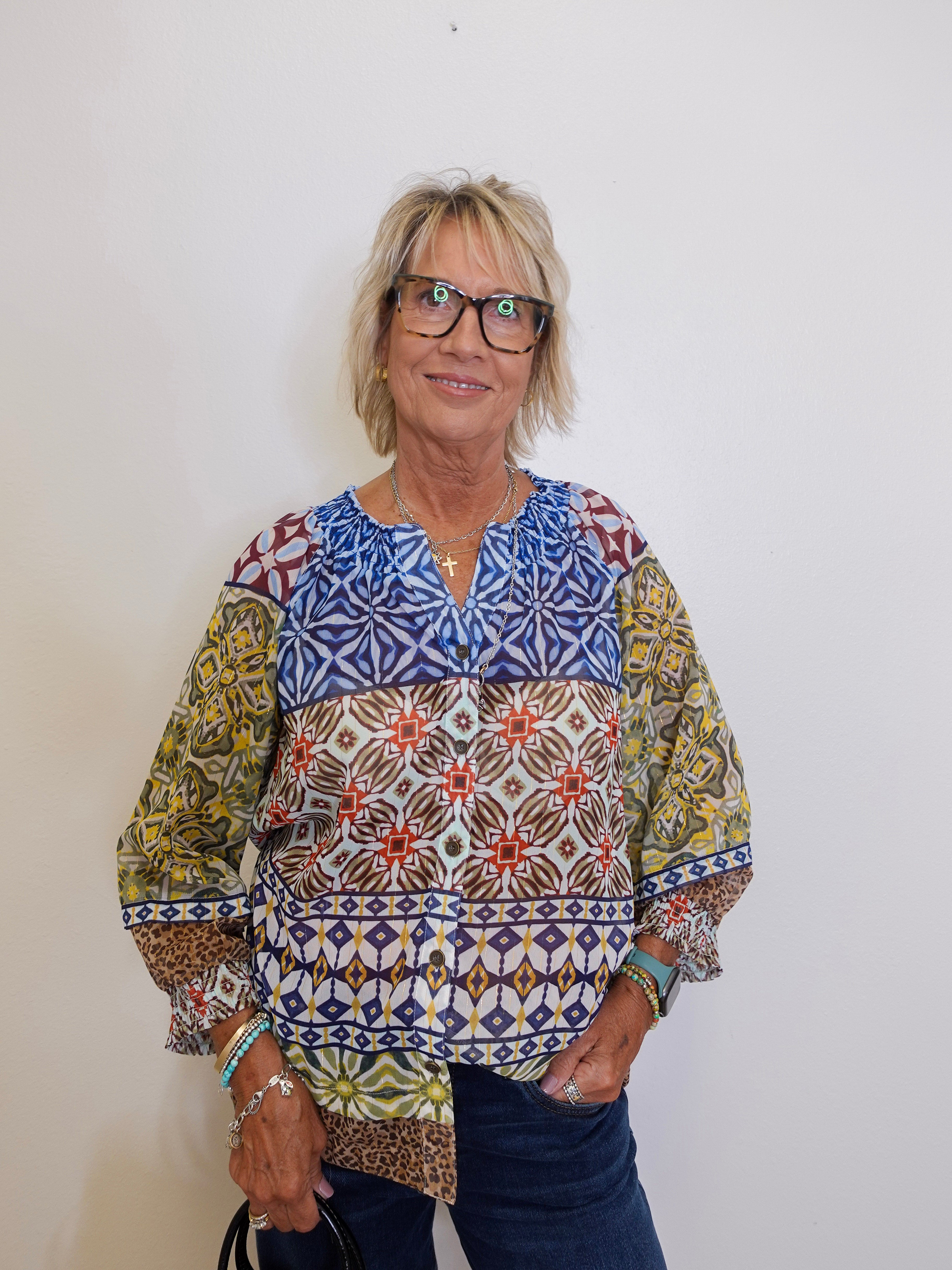 Woman wearing a colorful patterned blouse against a white background