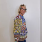 Woman wearing a colorful patterned sweater against a plain background