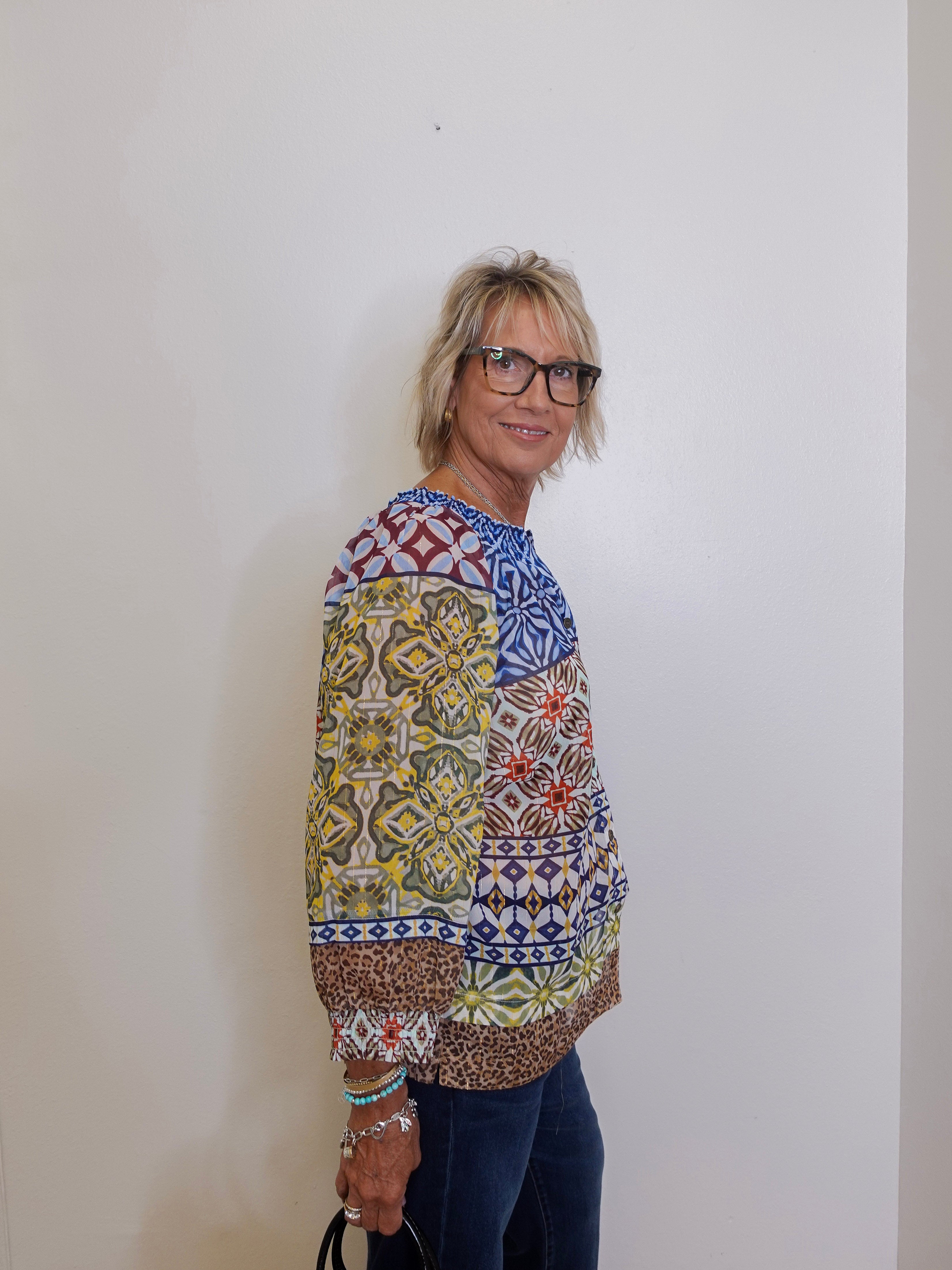 Woman wearing a colorful patterned sweater against a plain background