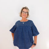 Woman wearing a blue blouse with white polka dots on a plain background
