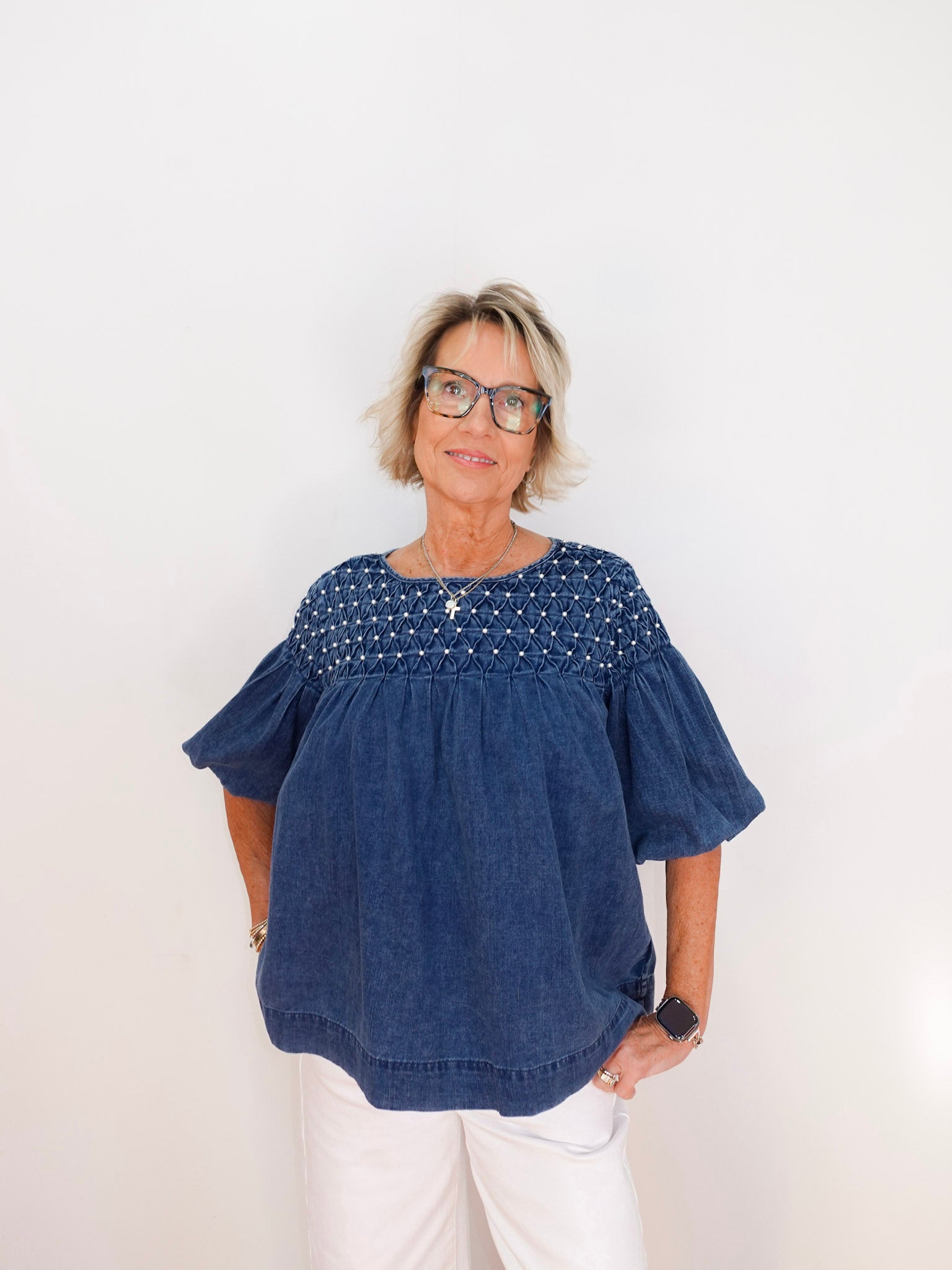 Woman wearing a blue blouse with white polka dots on a plain background