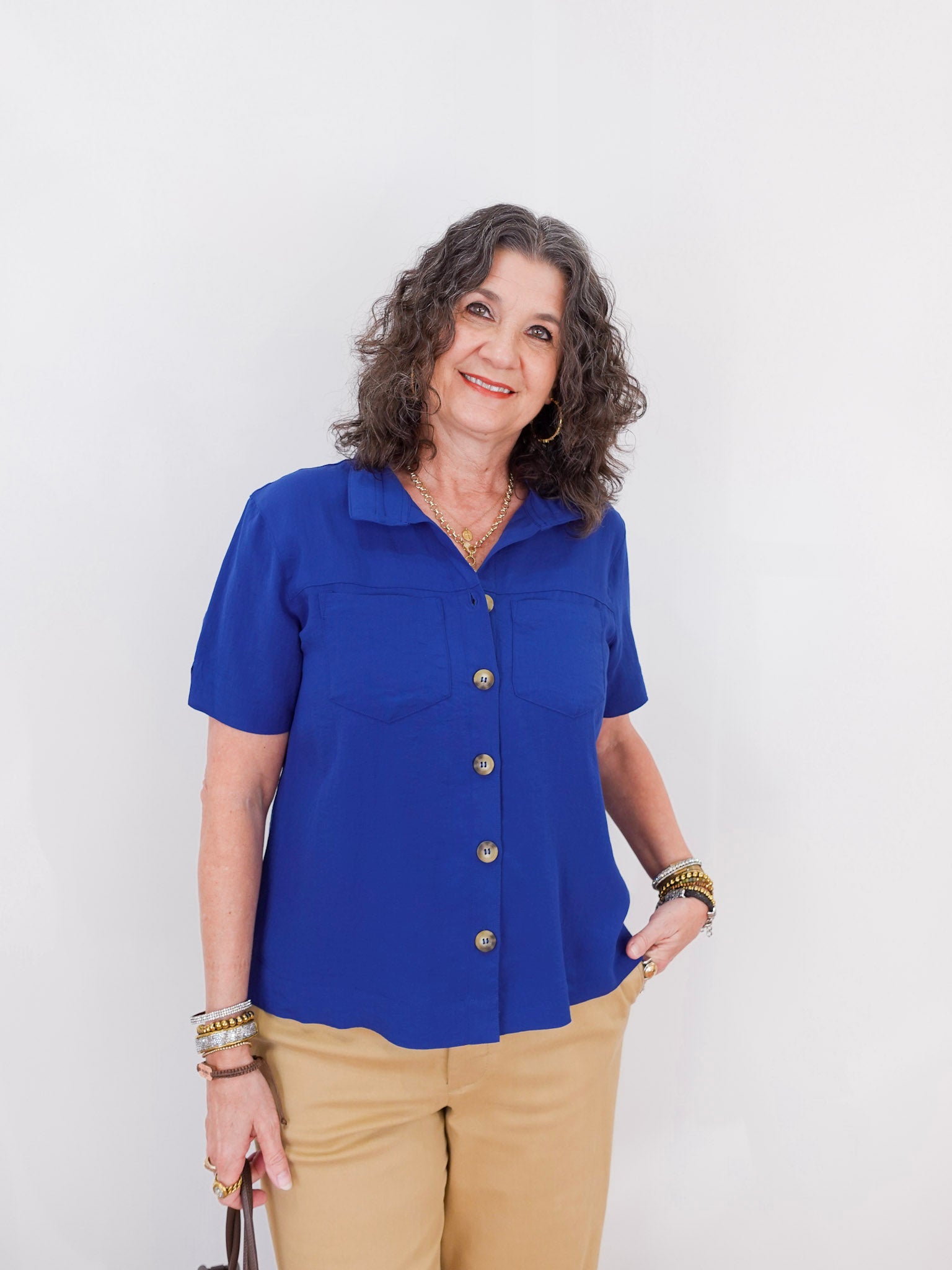 Woman wearing a blue blouse with gold buttons on a white background
