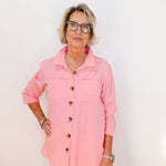 Woman wearing a pink shirt with buttons against a white background