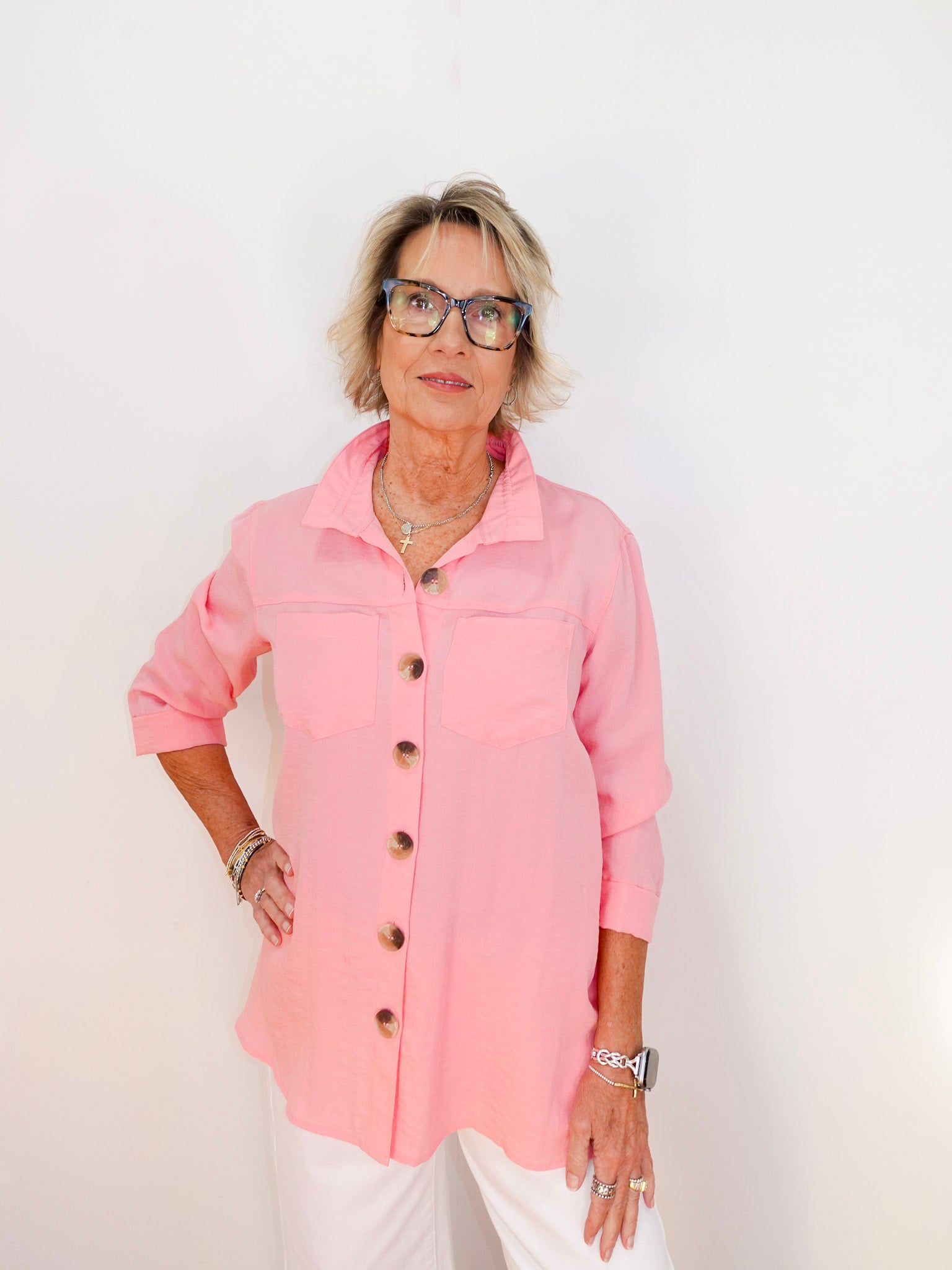 Woman wearing a pink shirt with buttons against a white background