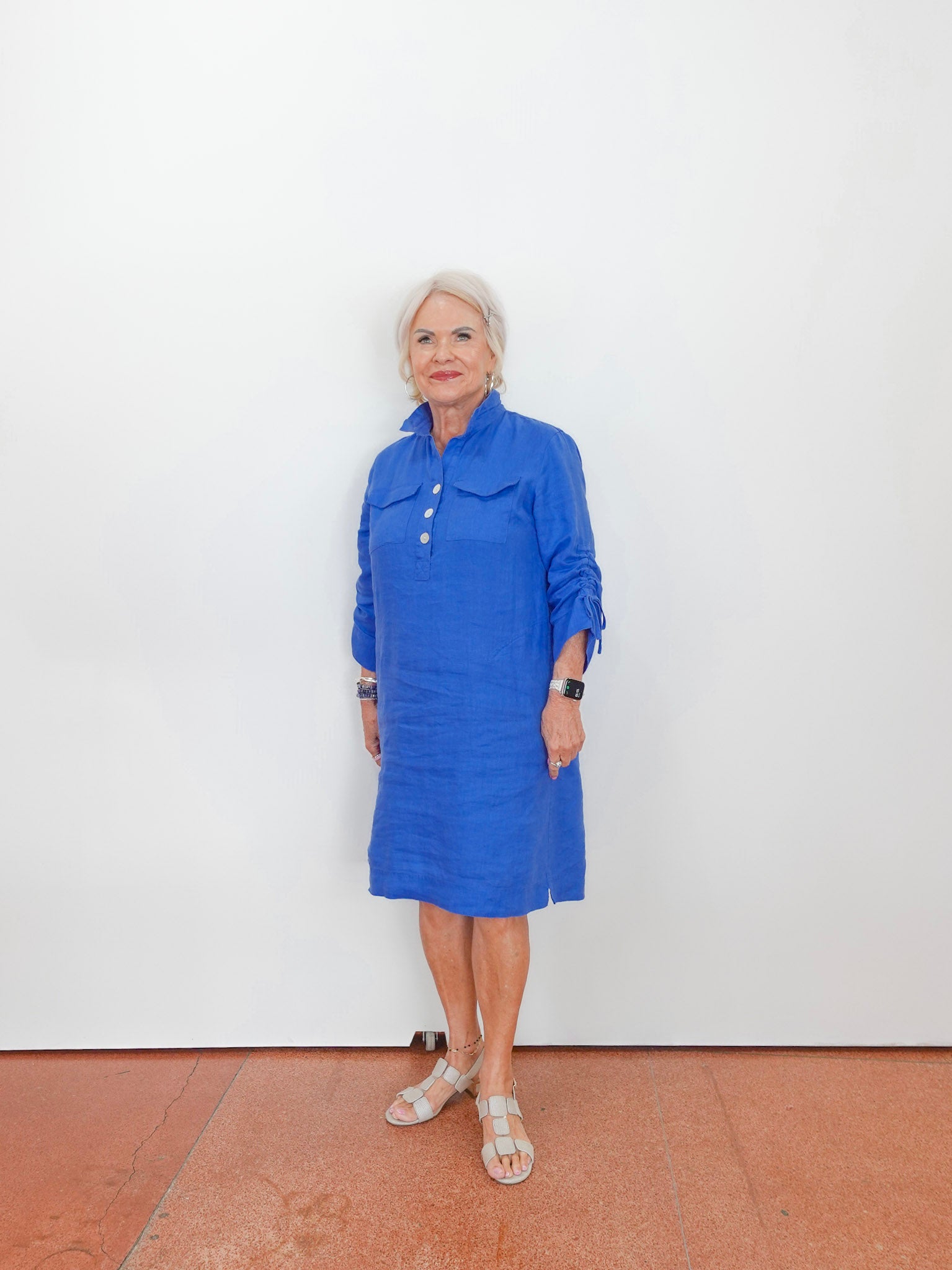 Woman wearing a blue dress standing against a white wall.